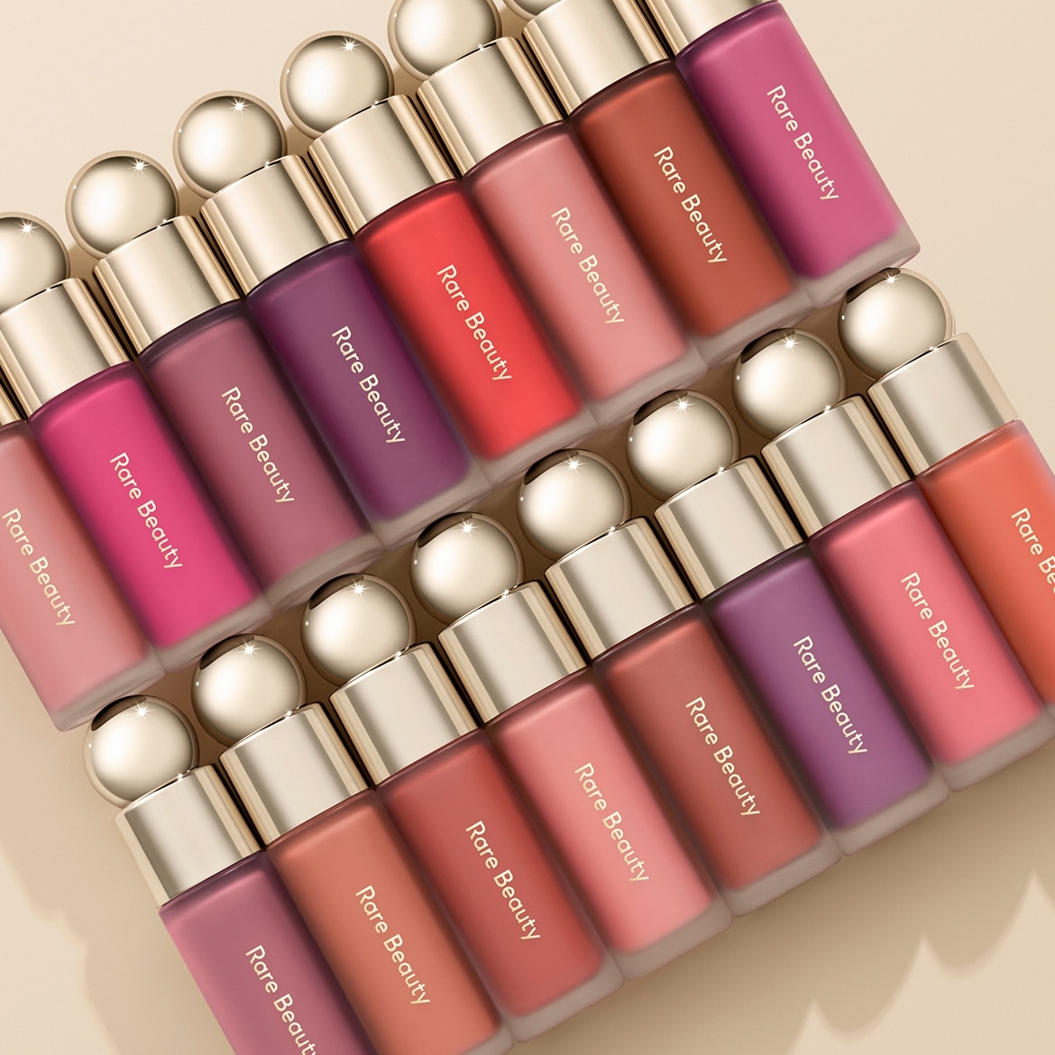 Eine Kollektion von Rare Beauty Lippenprodukten in verschiedenen Farbtönen, von sanften Rosatönen bis hin zu kräftigen Rottönen, präsentiert in eleganten, modernen Verpackungen.