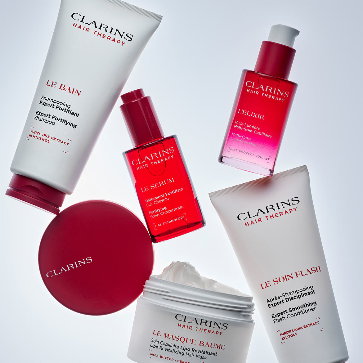 Das Clarins Hair Therapy Expert Fortifying Shampoo in einer weißen Tube mit rotem Deckel, angereichert mit weißem Iris-Extrakt und Panthenol, reinigt und stärkt das Haar.