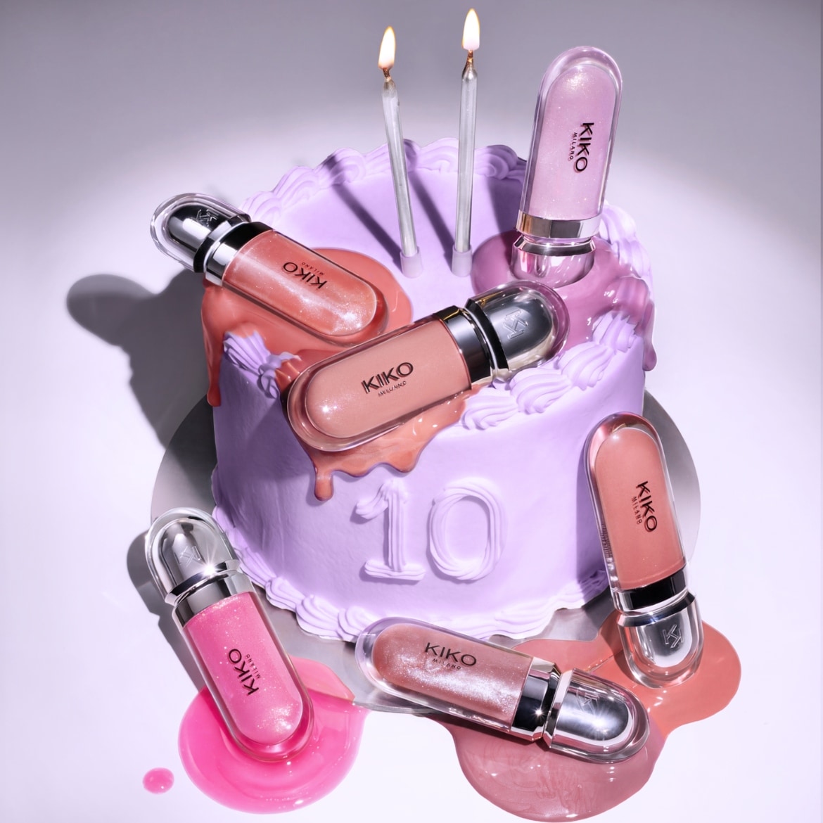 Auf einem lila Kuchen mit der Zahl 10 und brennenden Kerzen liegen Kiko Milano Lipglosse in verschiedenen Rosatönen.