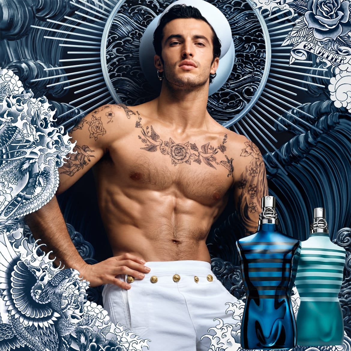 Ein tätowierter Mann mit einem Matrosenhut posiert neben zwei Jean Paul Gaultier Flakons, der eine in dunklem Blau mit schwarzen Streifen, der andere in hellem Türkis mit weißen Streifen.