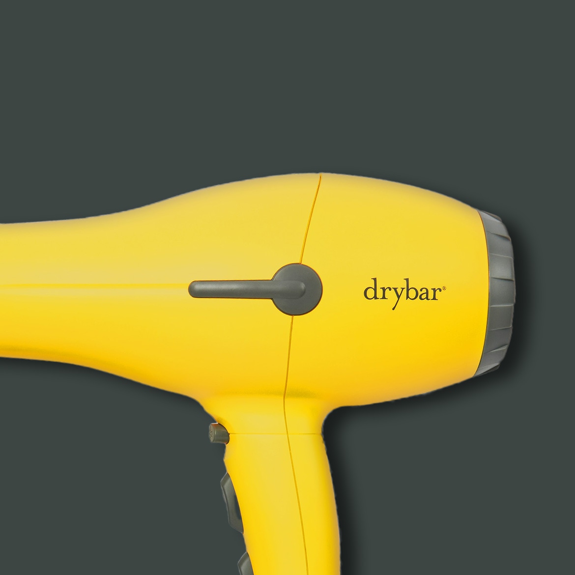 Gelber Drybar-Föhn mit grauem Griff und Düse vor einem dunklen Hintergrund.