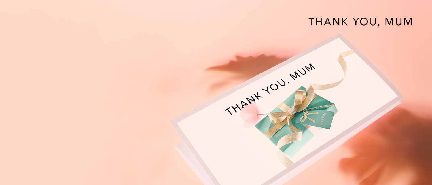 Eine Geschenkbox von Douglas in Mintgrün mit goldener Schleife und Anhänger, dazu der Text „THANK YOU, MUM“ auf einer Karte.