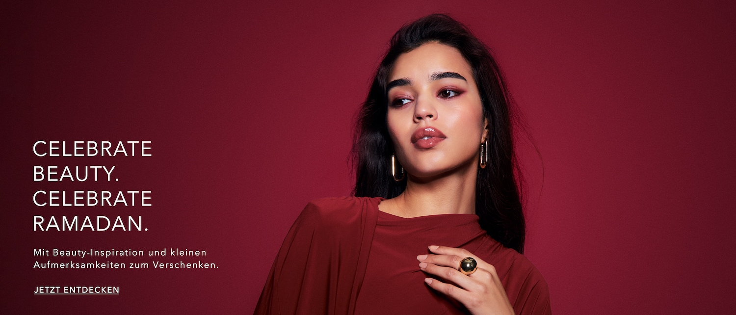 Vor einem weinroten Hintergrund posiert eine Frau mit dunklen, gewellten Haaren, goldenen Ohrringen und einem passenden Ring, während der Text "Celebrate Beauty. Celebrate Ramadan. Jetzt entdecken" zu lesen ist.