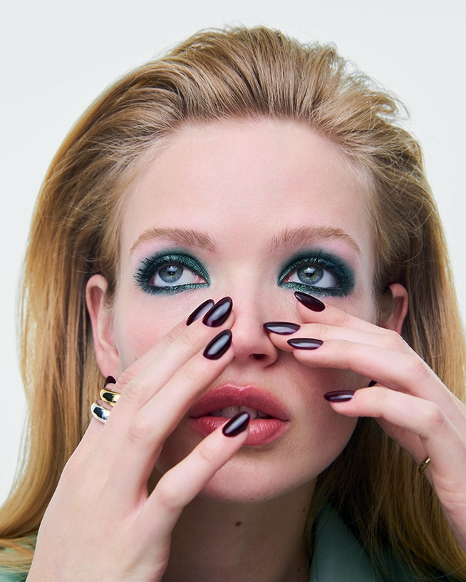 Nahaufnahme von Händen mit dunkel lackierten Nägeln vor einem herbstlich inspirierten Beauty-Look. Die Aufnahme steht für aktuelle Nageltrends und saisonale Nail-Polish-Farben.