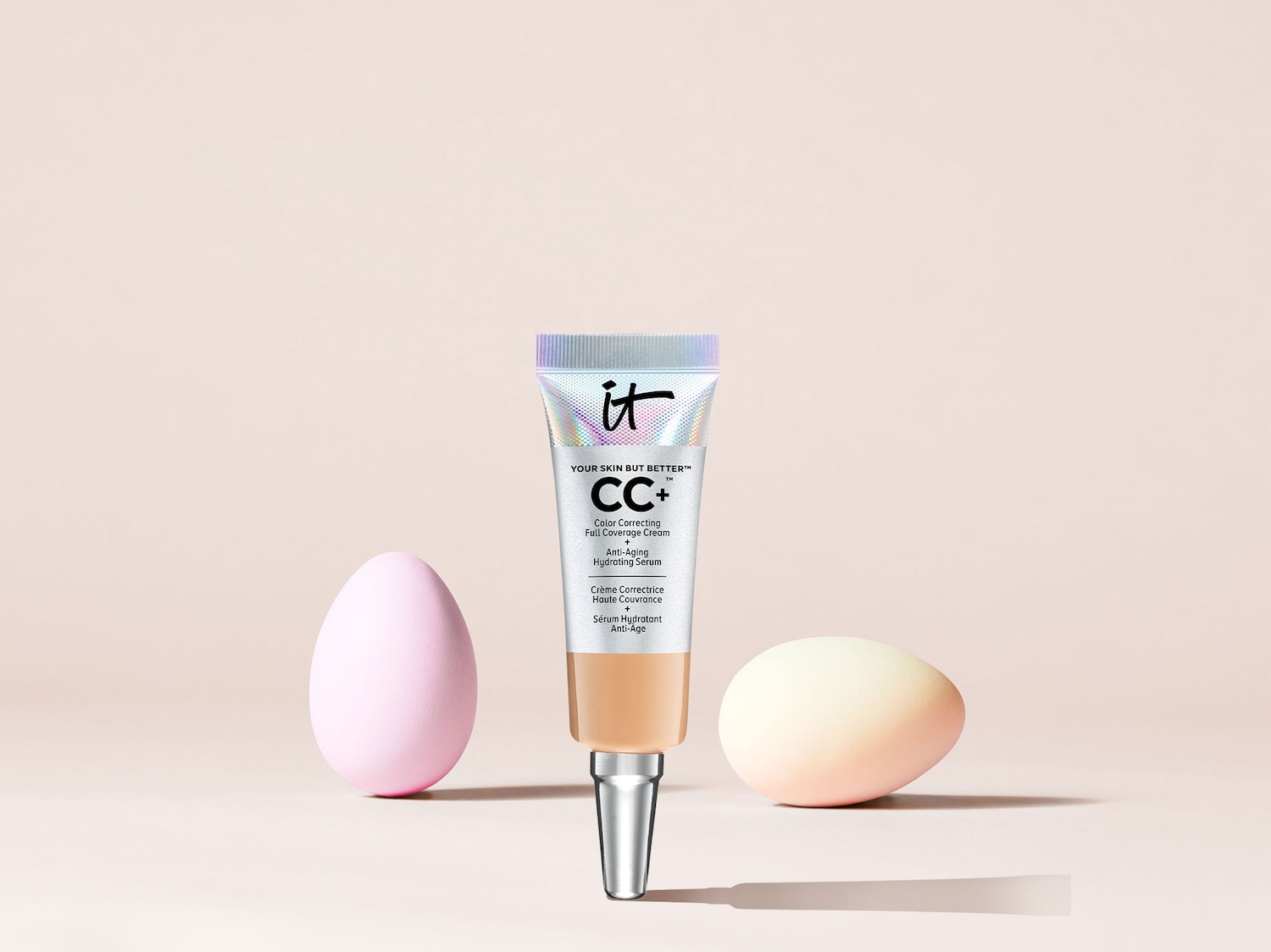 Entdecke die IT Cosmetics CC+ Color Correcting Full Coverage Cream, eine Anti-Aging-Feuchtigkeitspflege mit hoher Deckkraft, präsentiert in einer Tube mit silbernem Verschluss und begleitet von zwei Make-up-Schwämmchen.