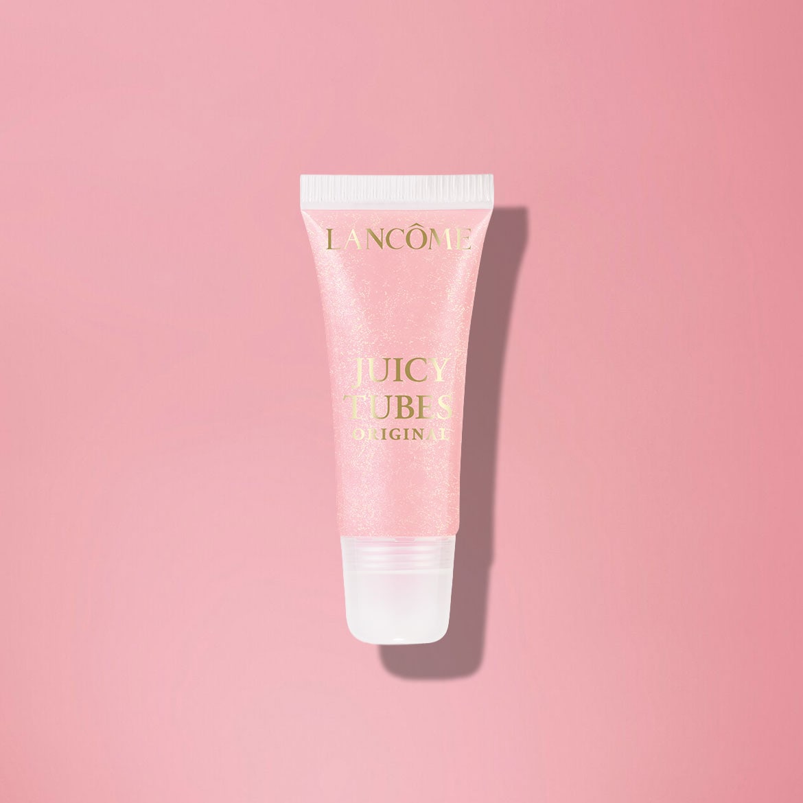 Hier ist ein Lancôme Juicy Tubes Original Lipgloss in einer schimmernden, hellrosa Tube mit goldener Schrift, die auf einem passenden rosa Hintergrund liegt.