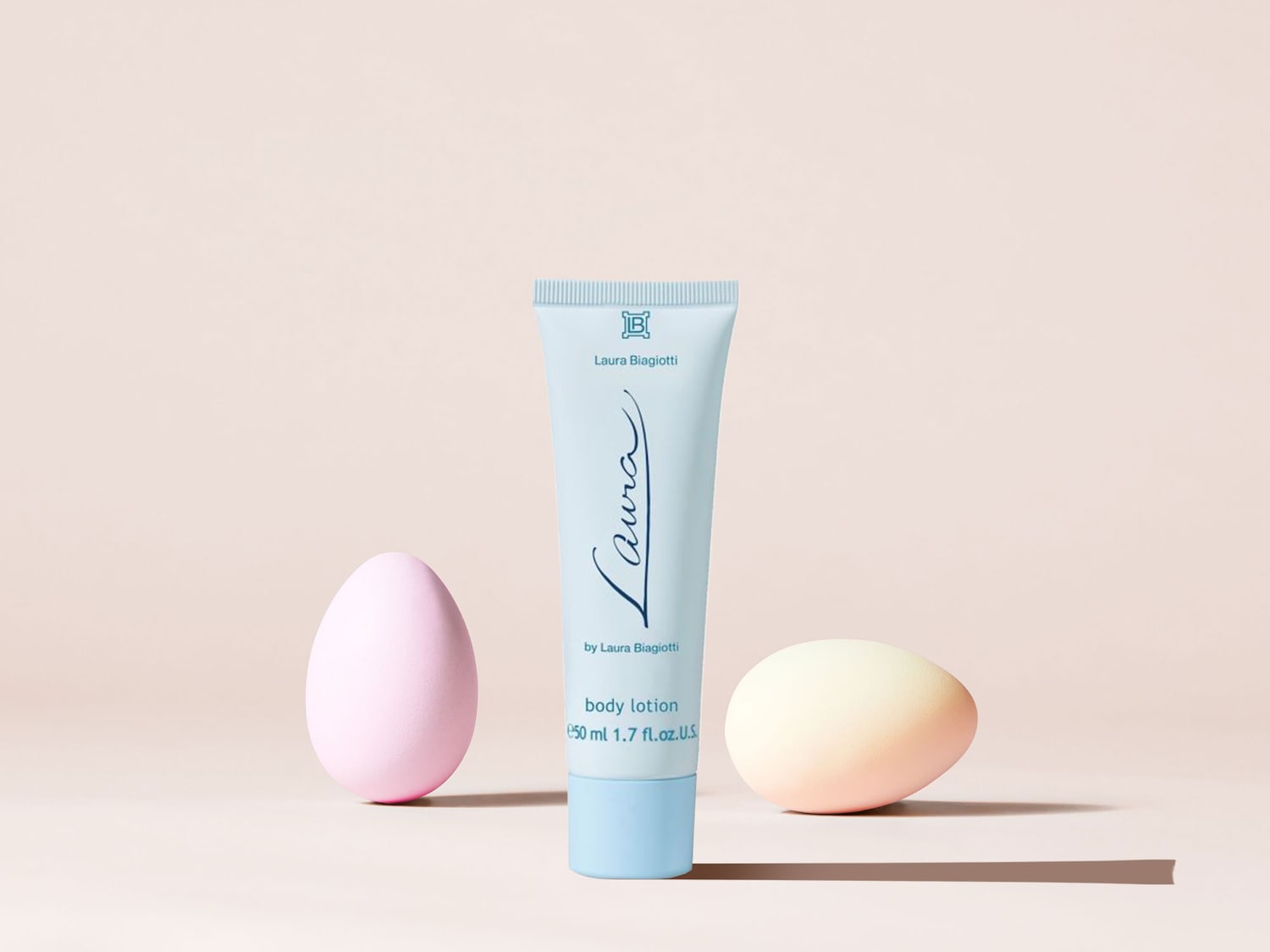 Hier ist eine hellblaue Tube Laura Biagiotti Bodylotion mit zwei Ostereiern, die eine festliche und pflegende Atmosphäre für die Hautpflege suggerieren.