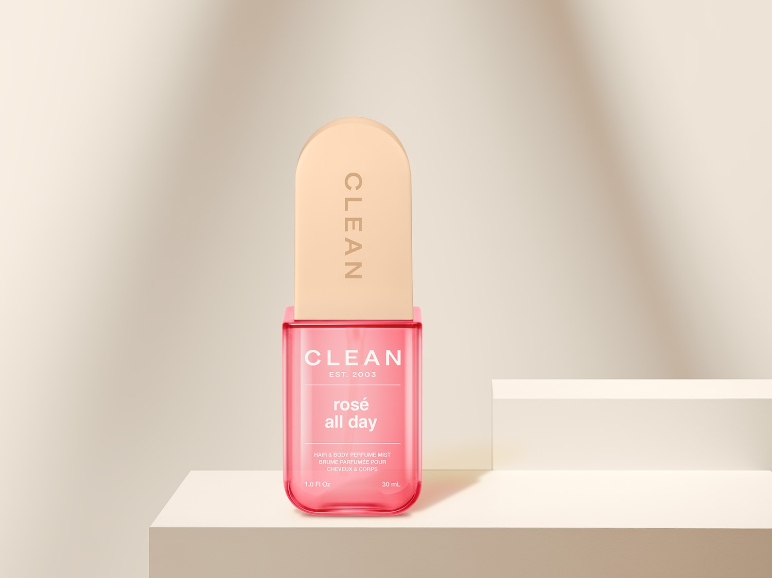 Die CLEAN Rosé All Day Hair & Body Perfume Mist präsentiert sich in einer transparenten, pinkfarbenen Flasche mit einem hellbeigen Verschluss, der den Markennamen trägt.