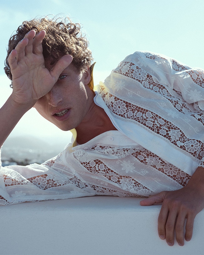 Ein Mann mit lockigem Haar schützt seine Augen vor der Sonne, um die Haut vor Schäden zu bewahren.