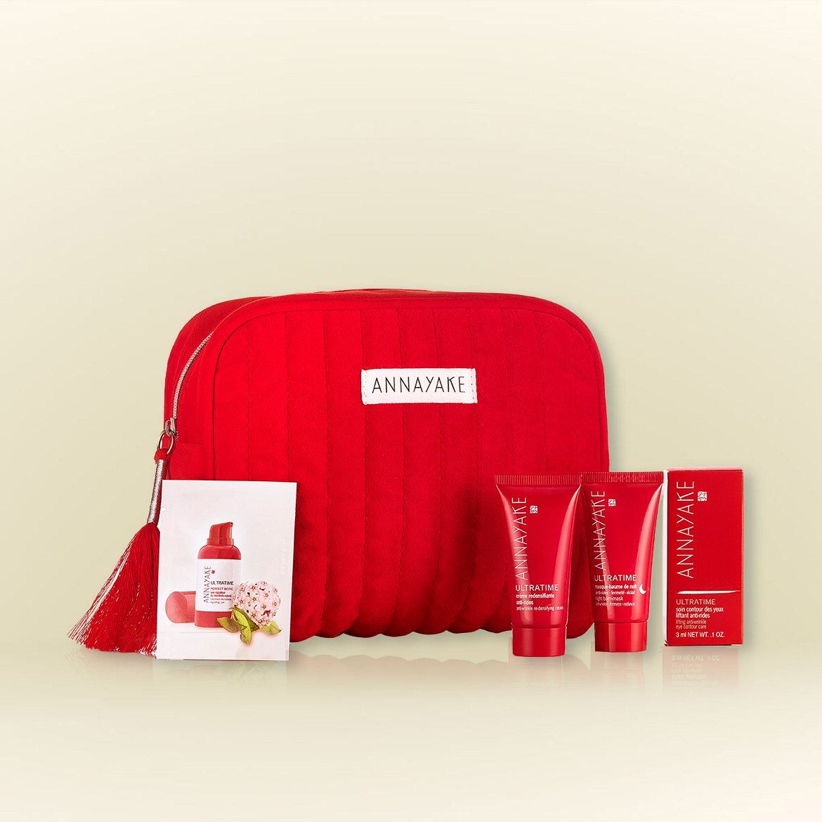 The image showcases a red Annayake Ultratime set, featuring a quilted cosmetic bag, skincare tubes, and a mask, all in matching red packaging.
