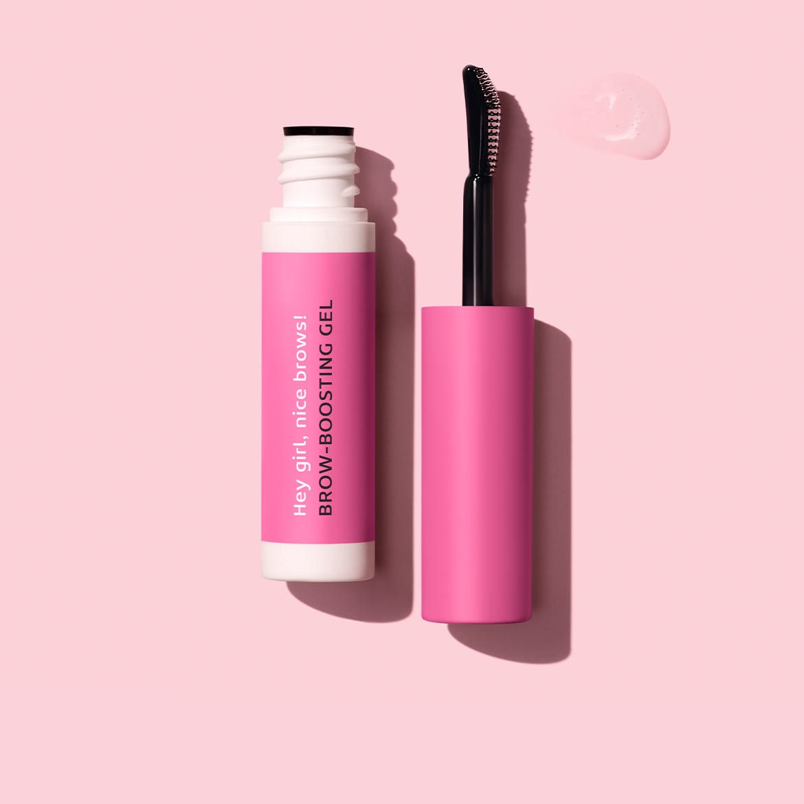 Auf hellrosa Grund liegen eine geöffnete, weiße Tube mit pinkfarbenem Etikett mit der Aufschrift „Hey girl, nice brows! BROW-BOOSTING GEL“ und eine pinkfarbene Bürste, neben der sich ein Gel-Klecks befindet.
