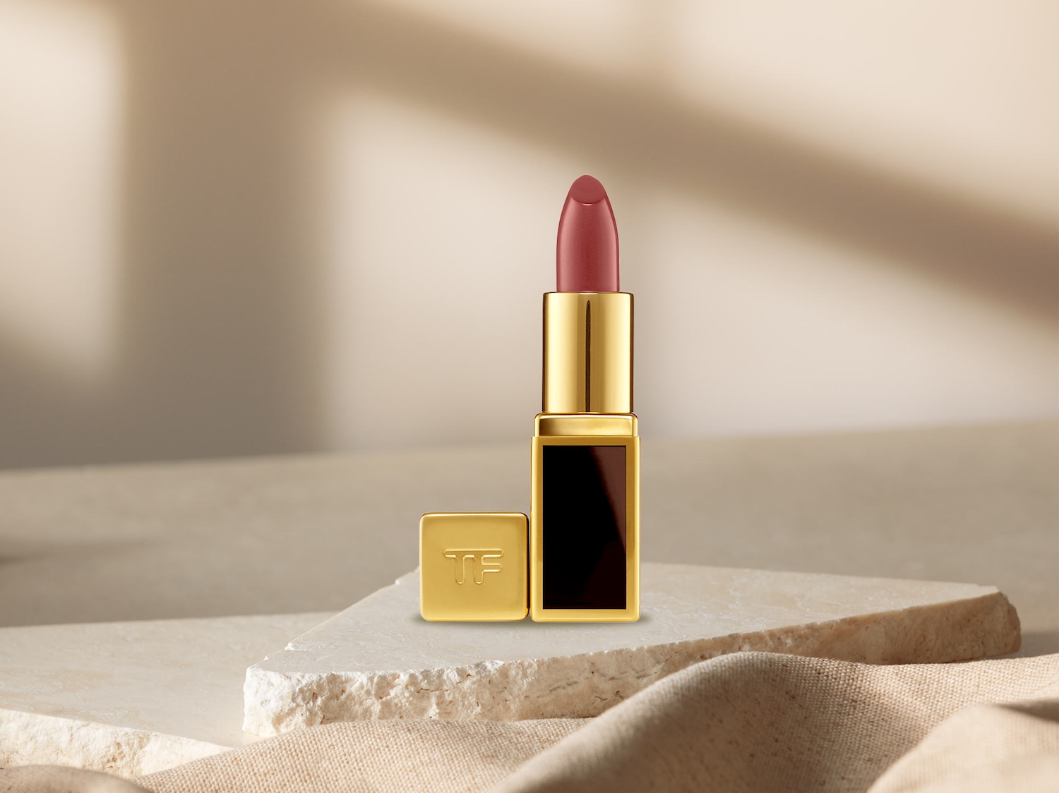 Dieser Tom Ford Lippenstift präsentiert sich in einer luxuriösen goldenen Hülle mit dem TF-Logo und einem eleganten, rosafarbenen Farbton.