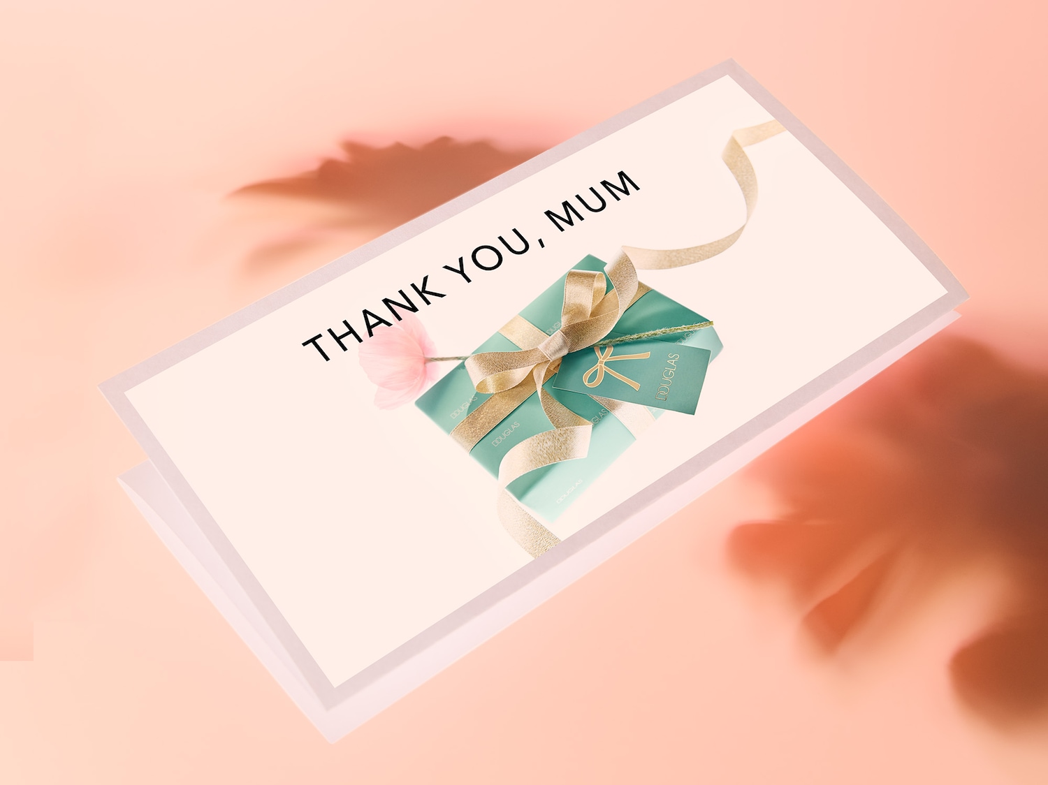 Eine Grußkarte mit der Aufschrift "DANKE, MAMA" und einem in Türkis verpackten Geschenk, das mit einer goldenen Schleife und einem Douglas-Etikett verziert ist.