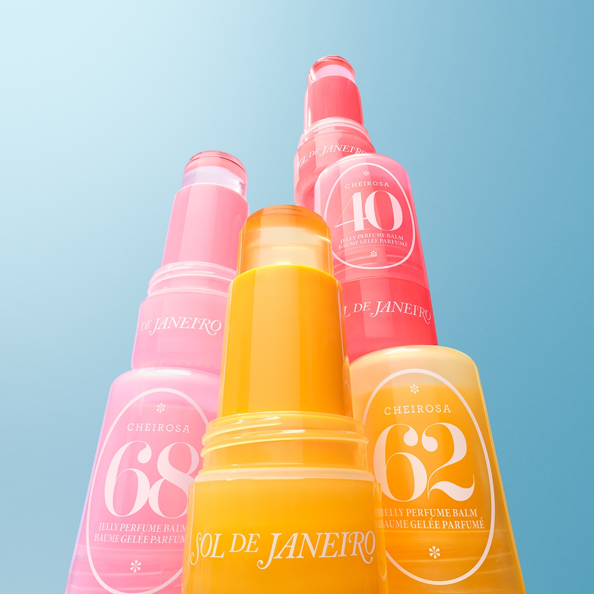 Nahaufnahme von Sol de Janeiro Jelly Parfüm Balsam in den Farben Gelb, Orange, Pink und Rot, die gestapelt sind und die Nummern 62, 68 und 40 tragen.