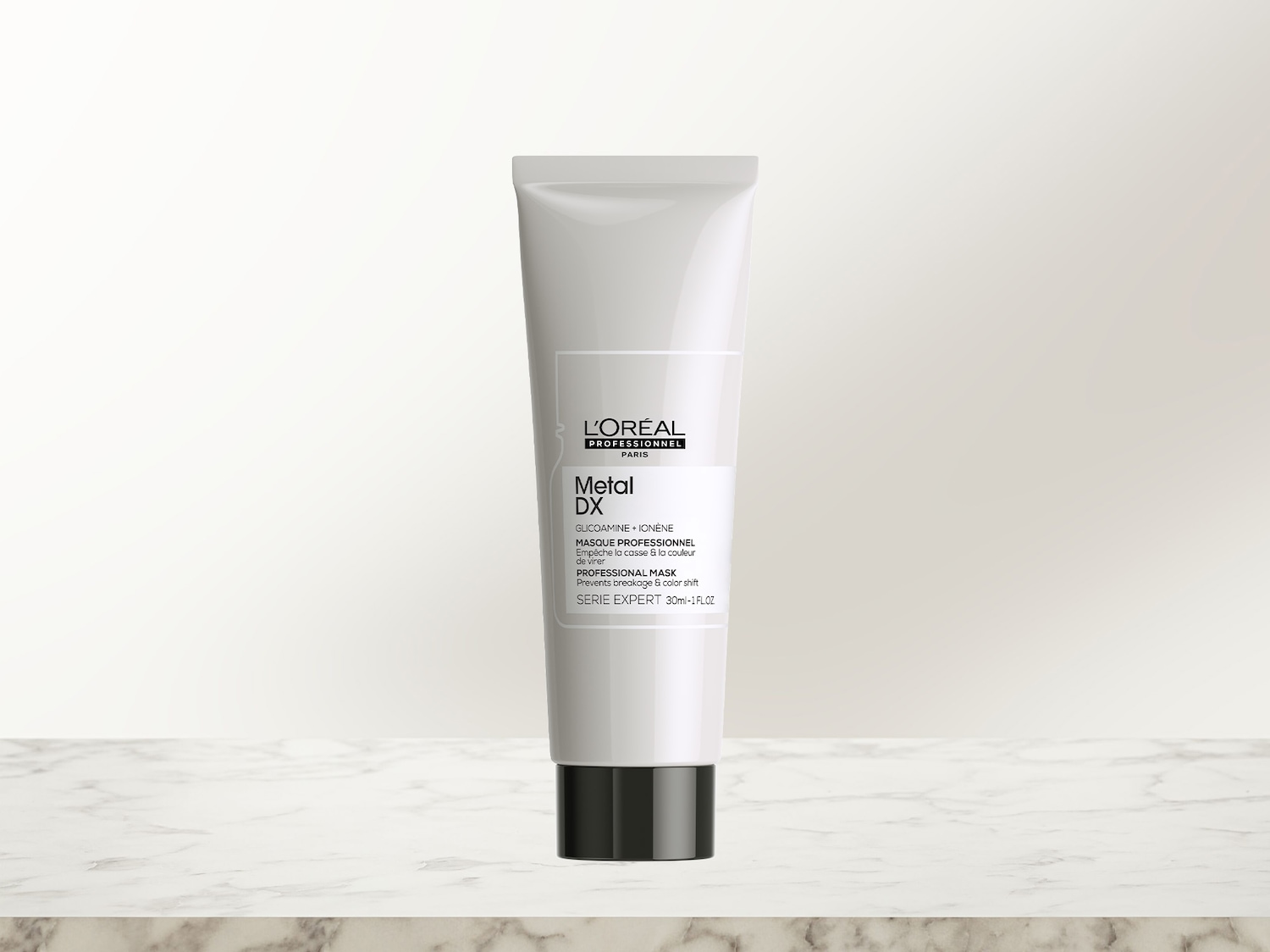 Eine weiße Tube der L'Oréal Professionnel Metal DX Haarmaske mit schwarzem Verschluss steht auf einer hellen Marmoroberfläche und schützt das Haar vor Haarbruch sowie Farbveränderungen.