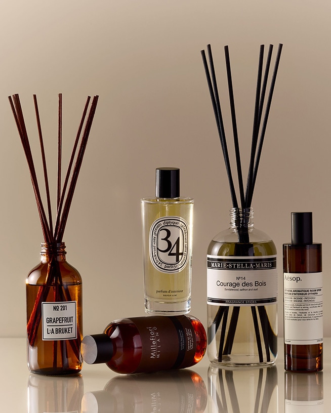 Verschiedene Laboratorio Olfattivo Raumdüfte, darunter Biancothè mit schwarzen Duftstäbchen in einer klaren Glasflasche, die auf einem Marmortisch stehen.